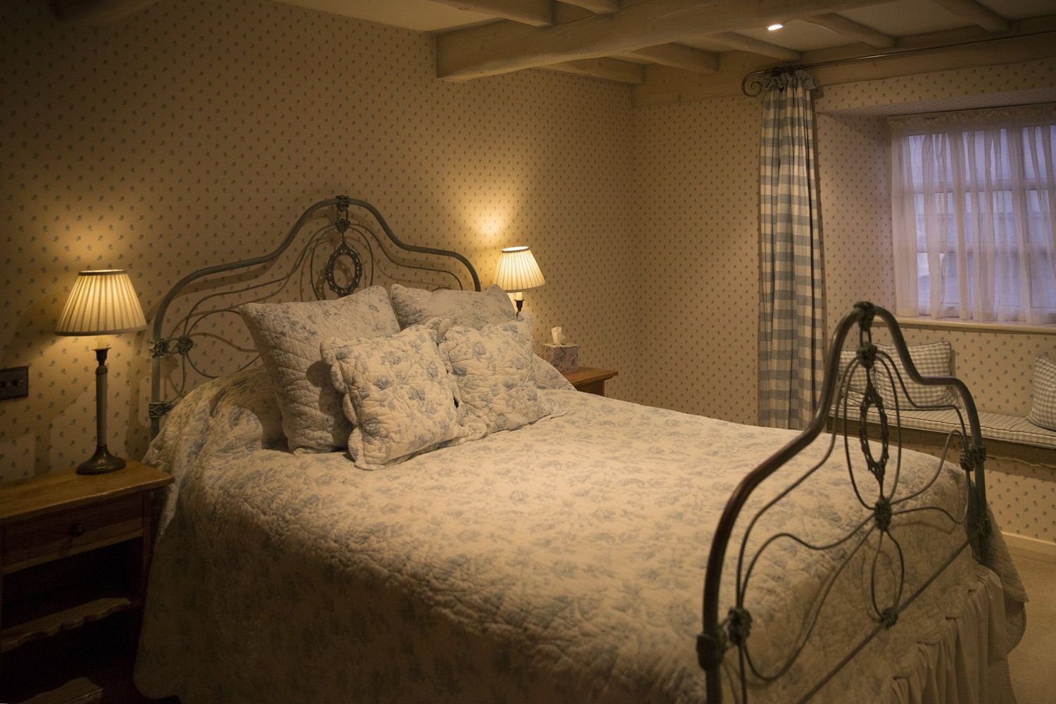 A large bed with a metal headboard and thick, white linens. 