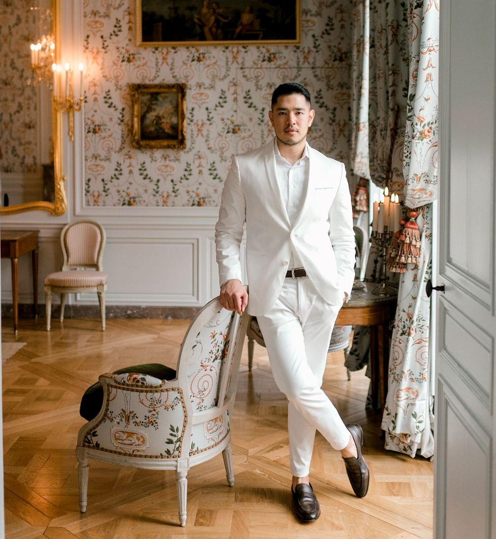 Cameron Lee, an esteemed luxury travel influencer, standing in a suite at the Airelles Chateau de Versailles.