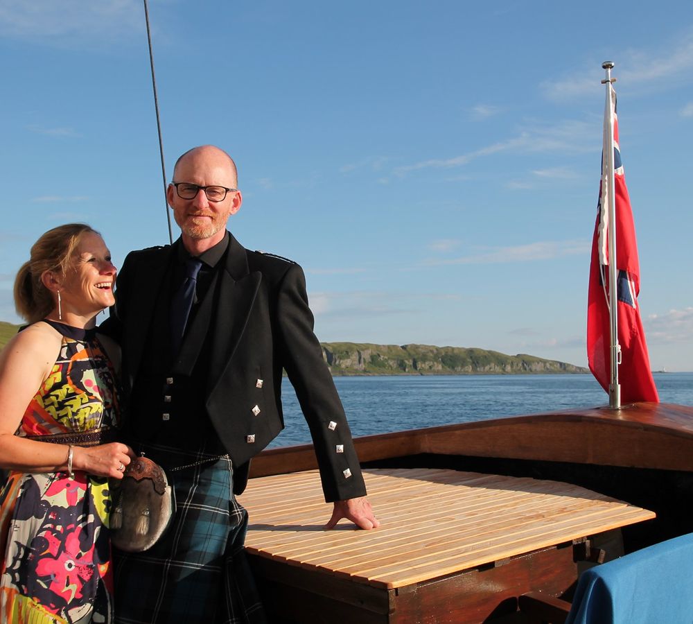 UK cruises provide an amazing immersion into UK culture. Here, a couple stands at the helm of the cruise ship, with the man wearing a traditional kilt. 