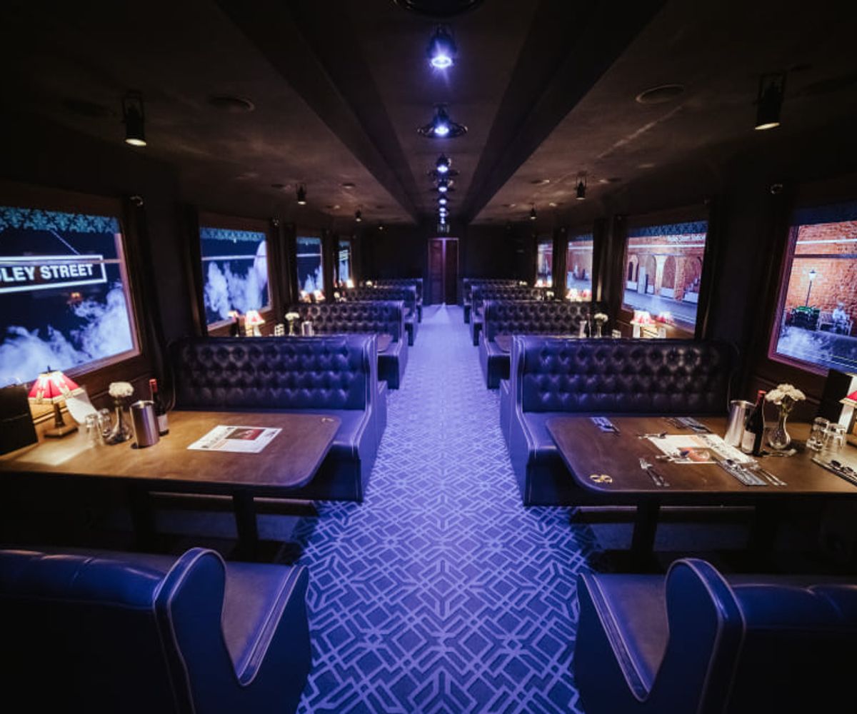The interior of The Murder Express, London's immersive murder mystery dining experience. Rows of tables mimic the layout of a train, with a long alley between for actors to perform around diners.for actors