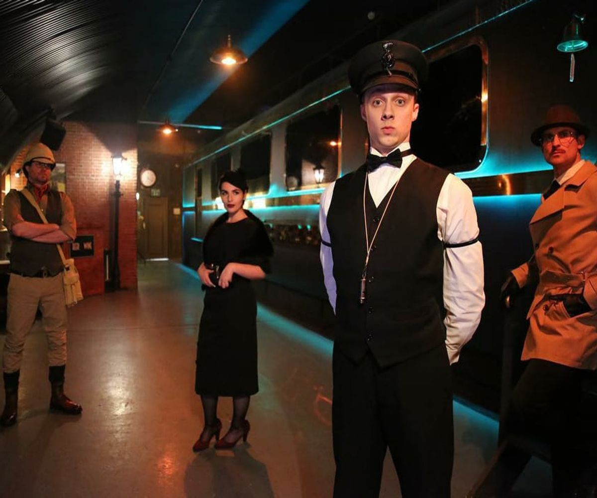 Characters stand on the platform of The Murder Express, London's immersive murder mystery dining experience.