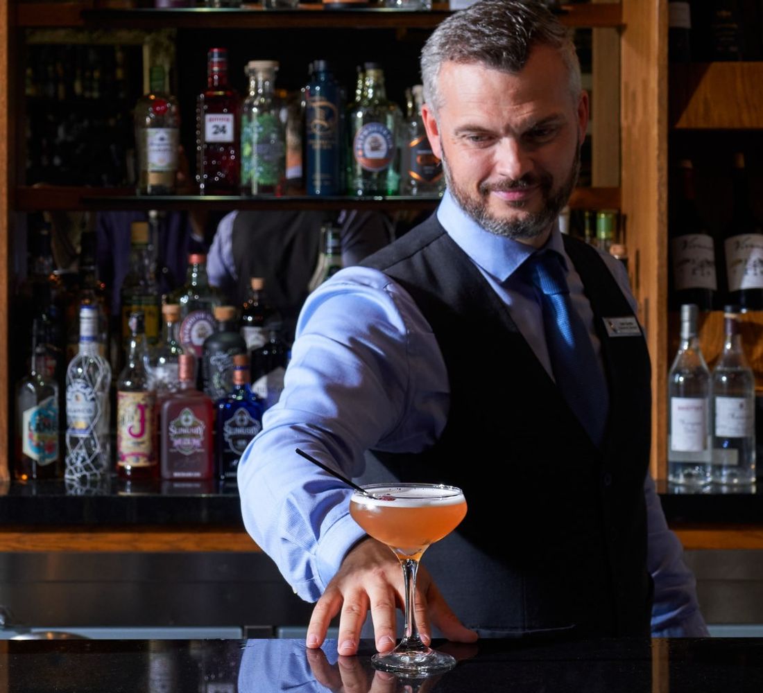 A bartender serves a cocktail at the bar in Rockliffe Hall.