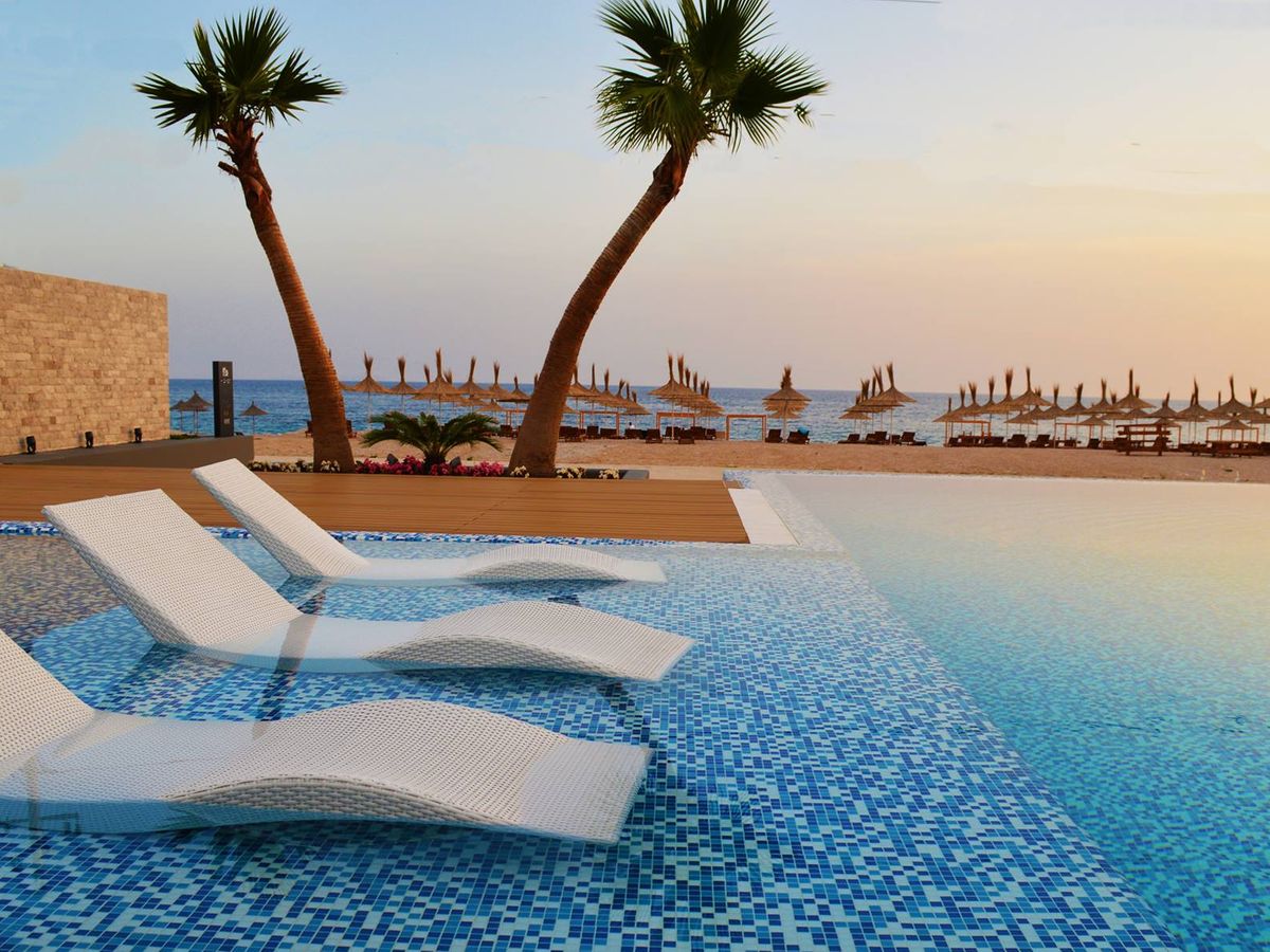 A large pool with palm trees and white loungers on the Albanian Riviera.