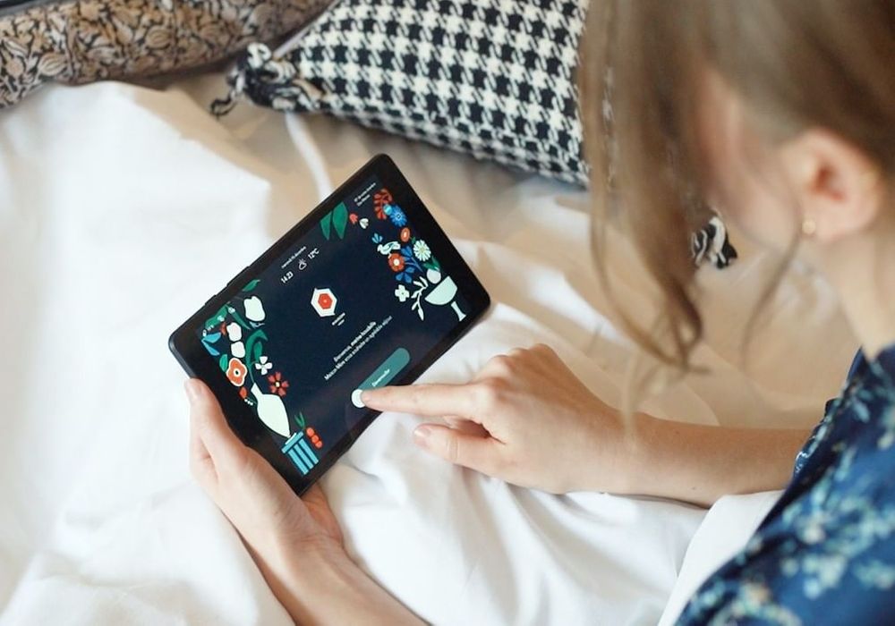 A woman swipes open on a Maison Mere room tablet.